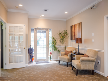 lobby area at Versailles apartments in Towson, MD with two comfy chairs, table and lamp
